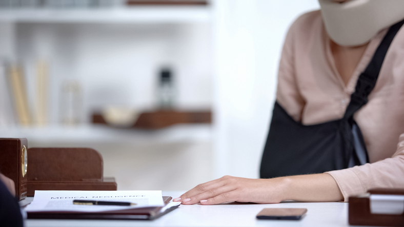 Femme devant un bueau avec le bras en écharpe
